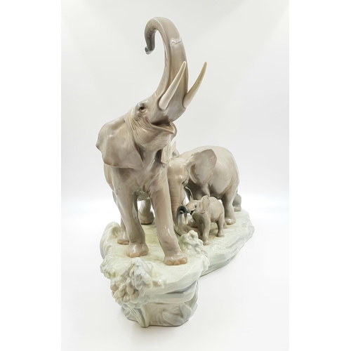 69 - This spectacular Lladro porcelain piece depicts a family of elephants ascending a rock-led by a trum... 