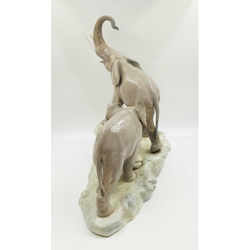 69 - This spectacular Lladro porcelain piece depicts a family of elephants ascending a rock-led by a trum... 