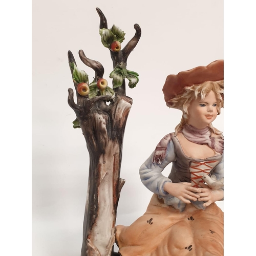 976 - A Capodimonte figure of a pretty girl playing with birds.