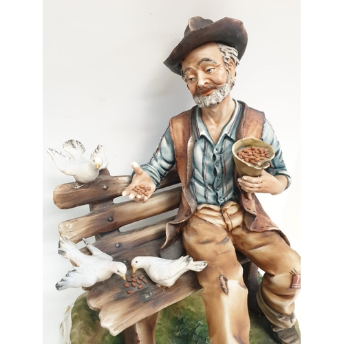 979 - A Capodmonte figure of an old man feeding birds. 30cm high x 24cm diameter.