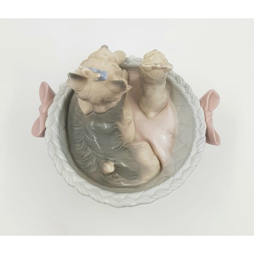 884 - A Lladro porcelain figurine of Terrier dogs in basket. Good condition. 10 x 13cm.