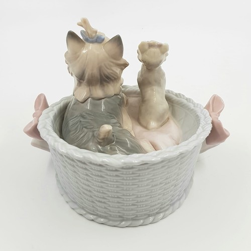 884 - A Lladro porcelain figurine of Terrier dogs in basket. Good condition. 10 x 13cm.