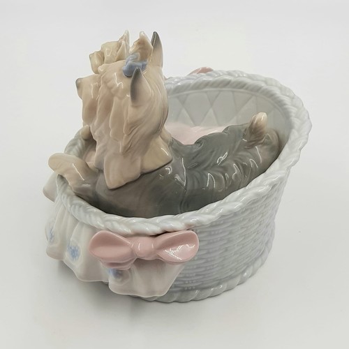 884 - A Lladro porcelain figurine of Terrier dogs in basket. Good condition. 10 x 13cm.