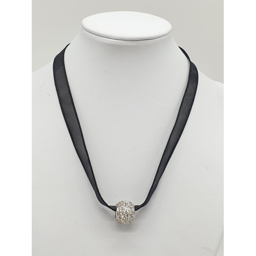 995 - Black fabric chocker with 18ct gold clasp and a 9ct decorative charm. 5.3g in weight.