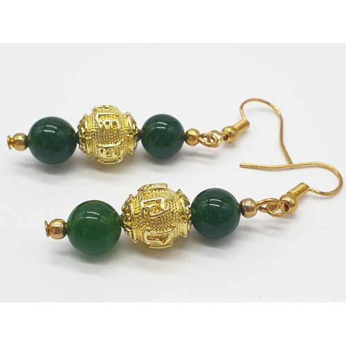 183 - A four row green jade necklace with Chinese gilded central beads and assorted Earrings. Necklace len... 