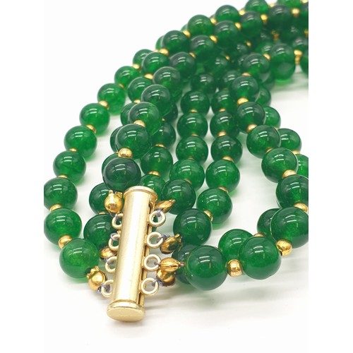 183 - A four row green jade necklace with Chinese gilded central beads and assorted Earrings. Necklace len... 