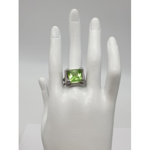 162 - A peridot sterling silver ring (stamped 925) and a matching earrings set presented in a vintage carv... 