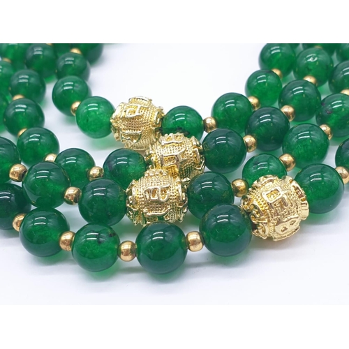 183 - A four row green jade necklace with Chinese gilded central beads and assorted Earrings. Necklace len... 