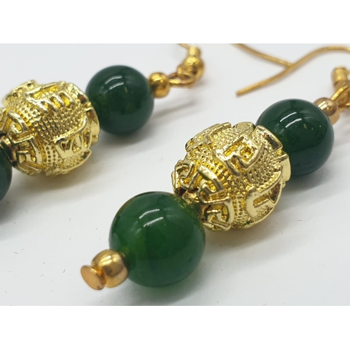 183 - A four row green jade necklace with Chinese gilded central beads and assorted Earrings. Necklace len... 