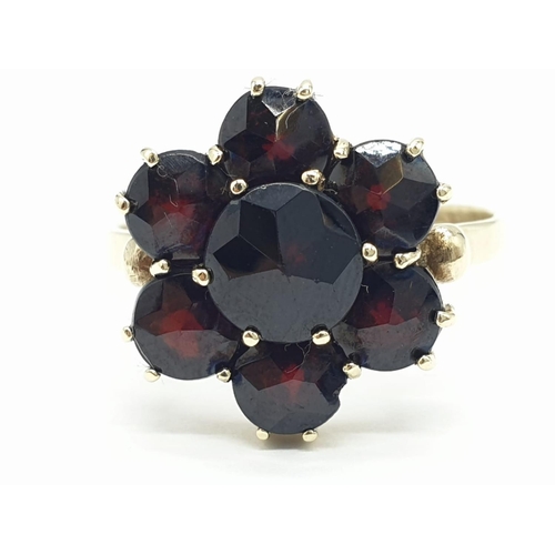 223 - Yellow gold ( tested as 9ct) garnet cluster ring flower design, weight 3.4g and size T