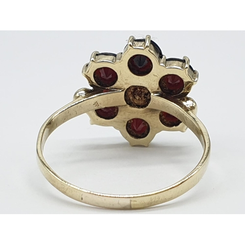 223 - Yellow gold ( tested as 9ct) garnet cluster ring flower design, weight 3.4g and size T