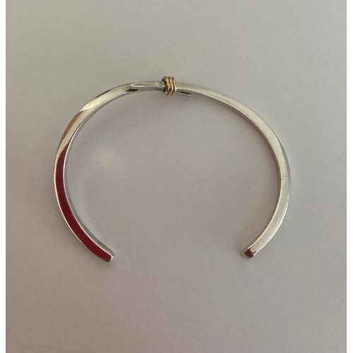 124 - Silver bangle in modernist crossover form having three golden contrasting hoops to top. Full silver ... 