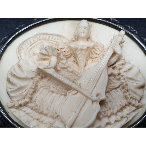 195 - An antique hand-carved ivory brooch on silver base - depicting a lady playing a cello. 20.5g total w... 