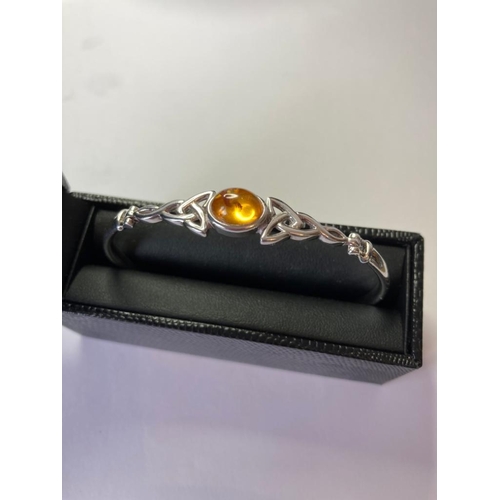 113 - Silver BANGLE having Celtic Knot design to the top with an amber centre stone.  Presented in Jewelle... 