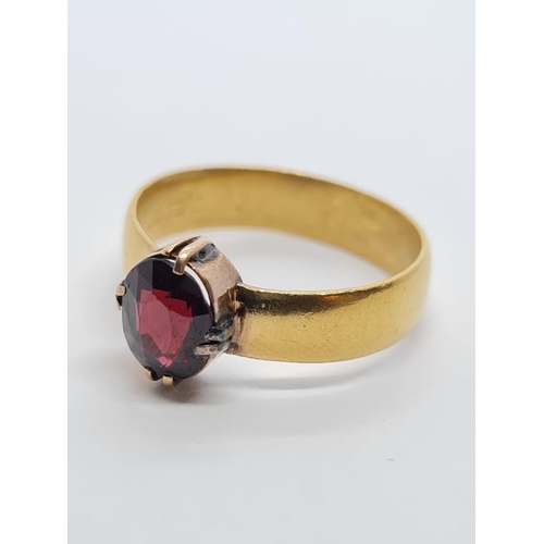 668 - 22 ct  Gold Band RING with an Oval Garnet Centre Stone.  4.9g  Size R.