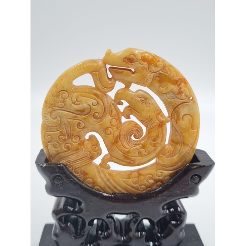 183 - A Chinese, carved, yellow-orange, jade disc (amulet?) with two protecting mythical beasts. Presented... 