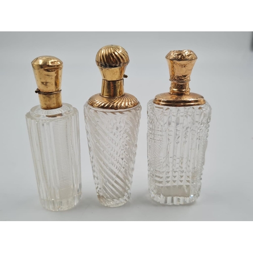 57 - 3 FRENCH 19TH CENTURY CUTGLASS PERFUME BOTTLES WITH 18CT GOLD TOPS, 137.3gms AND 9cms TALL.
