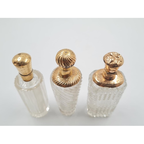 57 - 3 FRENCH 19TH CENTURY CUTGLASS PERFUME BOTTLES WITH 18CT GOLD TOPS, 137.3gms AND 9cms TALL.