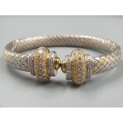 80 - AN OVAL 18CT YELLOW AND WHITE GOLD BANGLE WITH DIAMOND ENCRUSTING. 31.5gms.