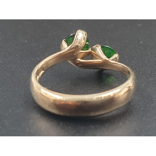 796 - A 9CT GOLD CROSSOVER RING WITH 2 GREEN STONES.
3.0gms AND SIZE L