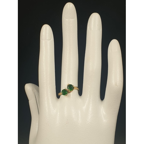 796 - A 9CT GOLD CROSSOVER RING WITH 2 GREEN STONES.
3.0gms AND SIZE L