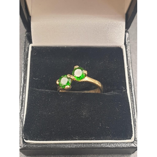 796 - A 9CT GOLD CROSSOVER RING WITH 2 GREEN STONES.
3.0gms AND SIZE L