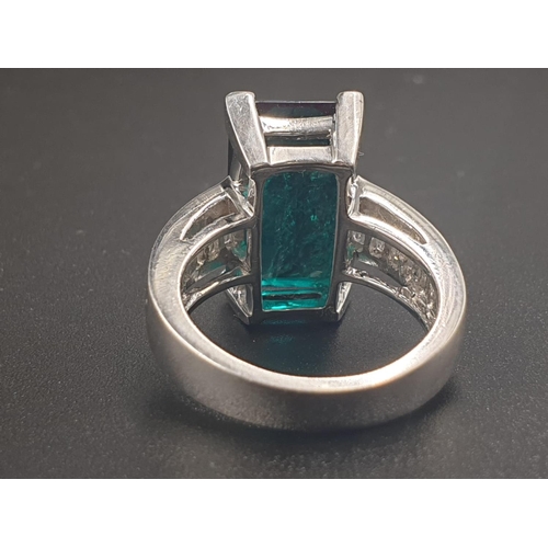 319 - A PLATINUM RING WITH A LARGE 8.5CT SYNTHETIC EMERALD WITH 12 NATURAL DIAMOND ON THE SHOULDERS TOTALL... 