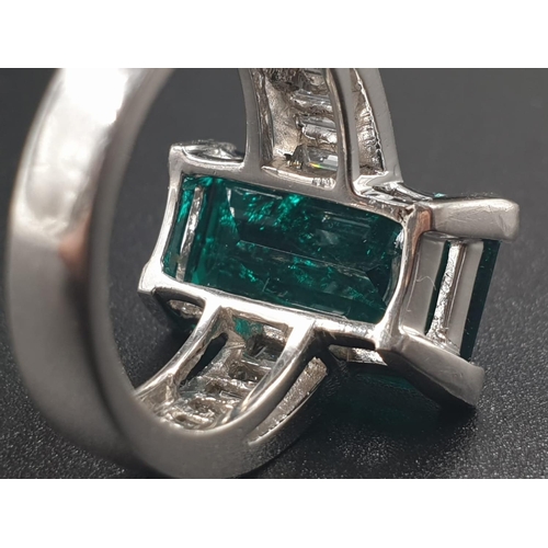 319 - A PLATINUM RING WITH A LARGE 8.5CT SYNTHETIC EMERALD WITH 12 NATURAL DIAMOND ON THE SHOULDERS TOTALL... 