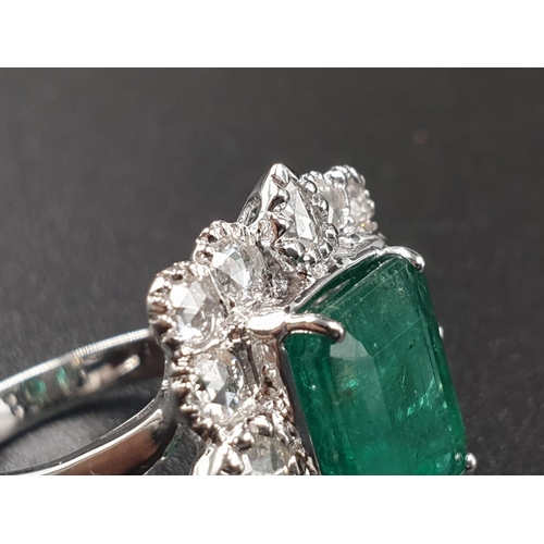 340 - AN 18CT WHITE GOLD RING SET WITH A LARGE EMERALD CUT NATURAL EMERERALD CENTRE STONE AND 16 ROSE CUT ... 