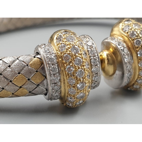 564 - AN OVAL 18CT YELLOW AND WHITE GOLD BANGLE WITH DIAMOND ENCRUSTING. 31.5gms.