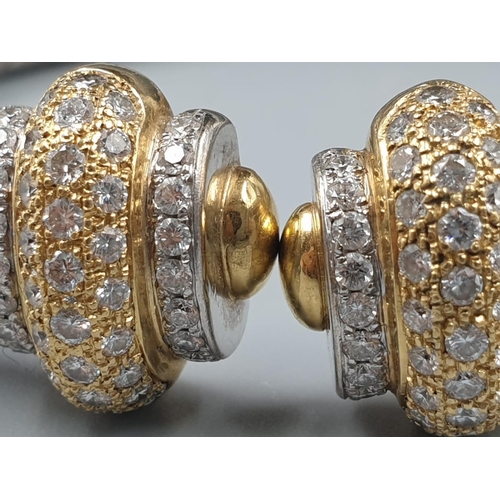 564 - AN OVAL 18CT YELLOW AND WHITE GOLD BANGLE WITH DIAMOND ENCRUSTING. 31.5gms.