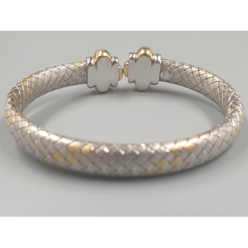 564 - AN OVAL 18CT YELLOW AND WHITE GOLD BANGLE WITH DIAMOND ENCRUSTING. 31.5gms.