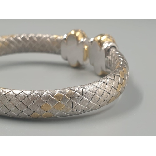 564 - AN OVAL 18CT YELLOW AND WHITE GOLD BANGLE WITH DIAMOND ENCRUSTING. 31.5gms.