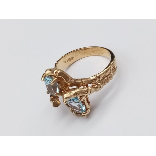 97 - 14k yellow gold crossover ring with blue stones, weight 5.4g and size L