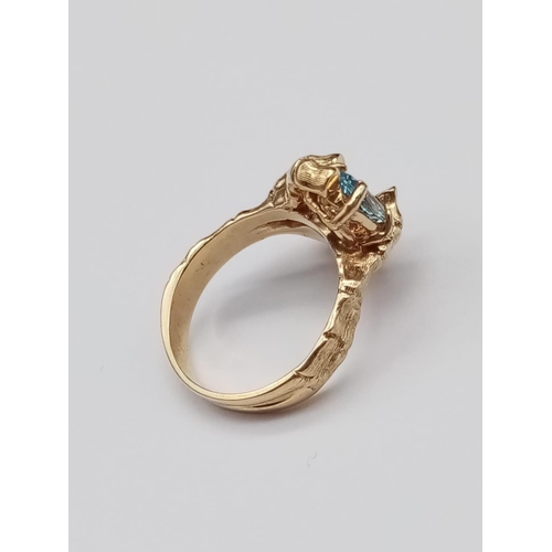 97 - 14k yellow gold crossover ring with blue stones, weight 5.4g and size L