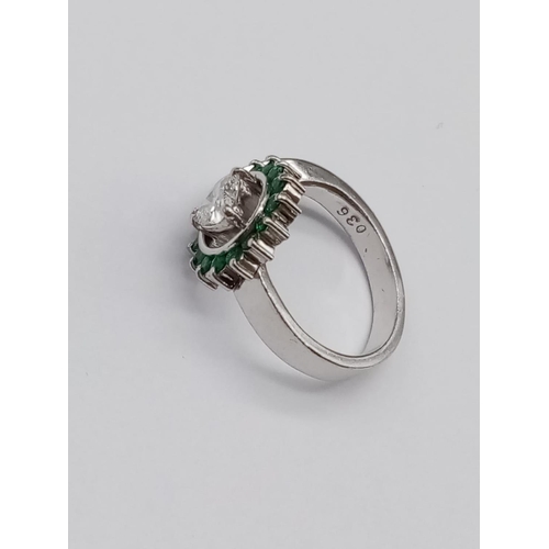 110 - A PLATINUM RING CONTAINING A HEART SHAPED CENTRAL DIAMOND SURROUNDED BY EMERALDS.
6.8gms     SIZE K/... 