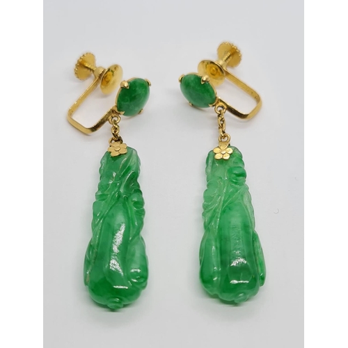 80 - Pair of 21k yellow Oriental gold earrings with natural carved Jade, weight 6.16g and 4cm drop approx