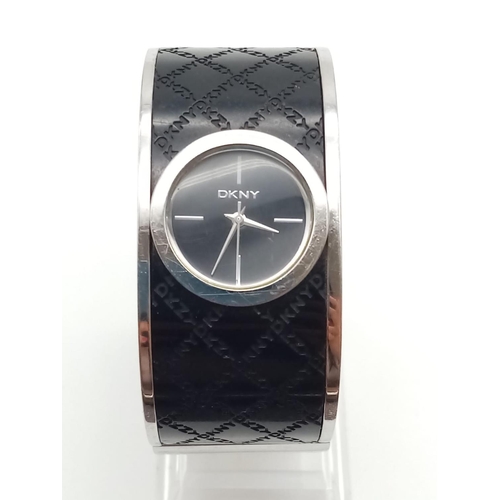 317 - DKNY Ladies Dress Watch. Black Monogramed Leather on Stainless Steel Strap. Black Dial. As found.