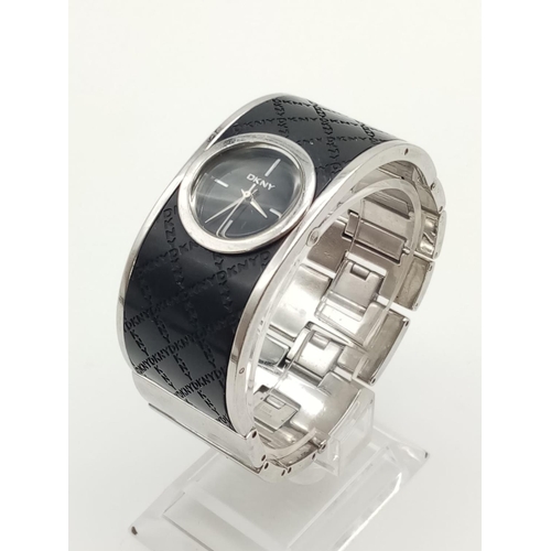 317 - DKNY Ladies Dress Watch. Black Monogramed Leather on Stainless Steel Strap. Black Dial. As found.