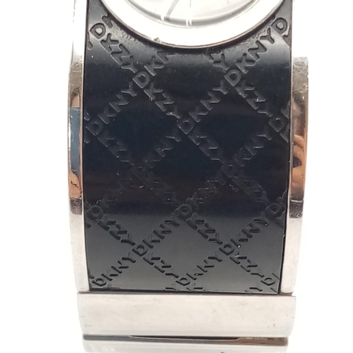 317 - DKNY Ladies Dress Watch. Black Monogramed Leather on Stainless Steel Strap. Black Dial. As found.