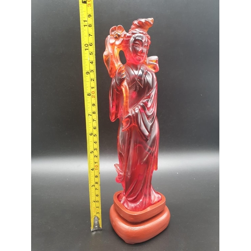 168 - A traditional, Chinese, hand carved, amber resin, statue of a lady holding an oversized flower, on a... 