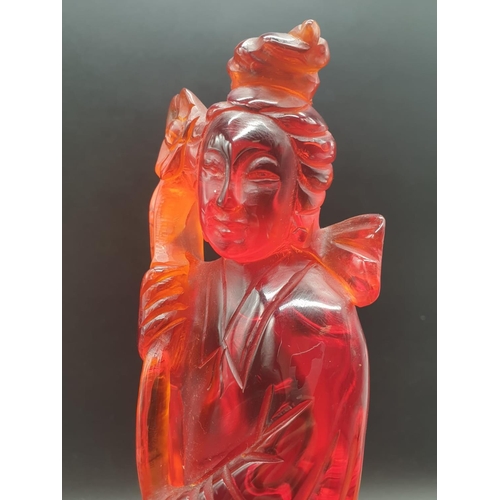 168 - A traditional, Chinese, hand carved, amber resin, statue of a lady holding an oversized flower, on a... 