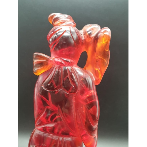 168 - A traditional, Chinese, hand carved, amber resin, statue of a lady holding an oversized flower, on a... 