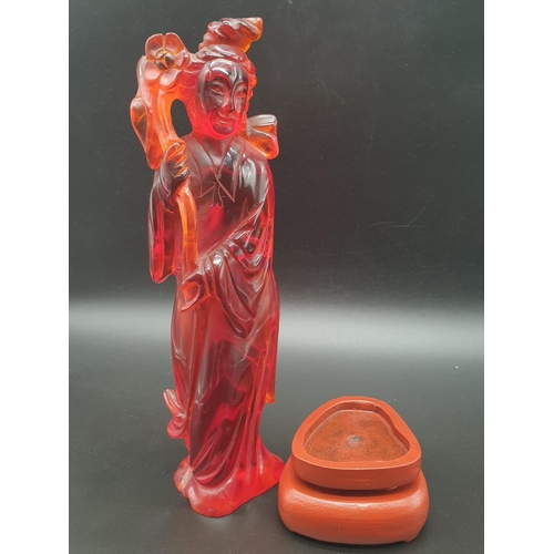 168 - A traditional, Chinese, hand carved, amber resin, statue of a lady holding an oversized flower, on a... 