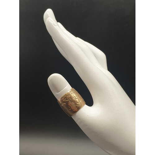 71 - A fully hallmarked, 9 K yellow gold, barrel shaped ring, with an engraved, flower design on surface,... 