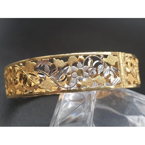 83 - A platinum (900) bangle with intricate white and yellow flower on vines design. A screw top clasp al... 