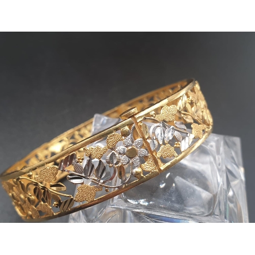 83 - A platinum (900) bangle with intricate white and yellow flower on vines design. A screw top clasp al... 