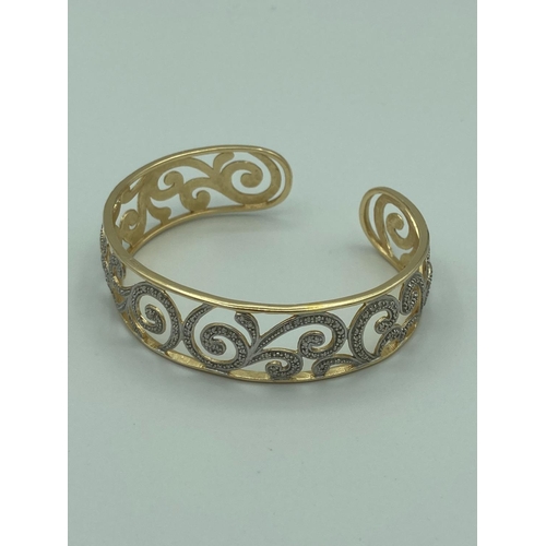 181 - SILVER BANGLE in pierced scroll form,having Silver marcasite detail with gilded silver borders.