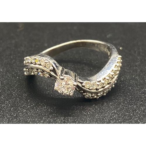 746 - A 9K White Gold Diamond Wave Ring. Centre diamond with diamond waves either sides. 0.75ct Size L. 3g... 