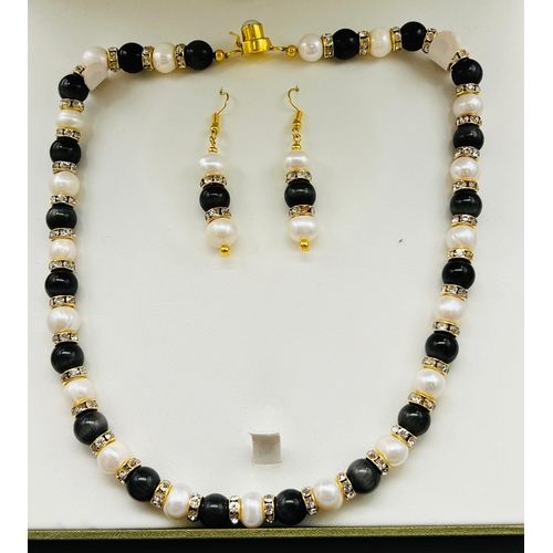 85 - A very feminine, genuine pearl and cat’s eyes necklace and earring set, with cubic zirconia. In a pr... 